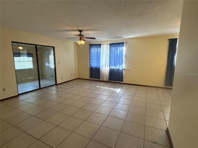 tiled empty room featuring a textured ceiling, ceiling fan, and plenty of natural light