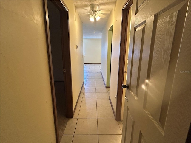 hall with a textured ceiling and light tile patterned floors