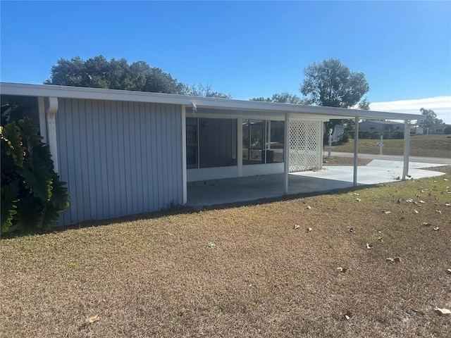 rear view of house featuring a patio, a yard, and a sunroom