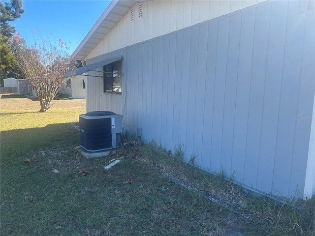 view of side of home featuring a yard and central AC