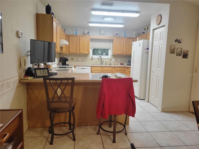 kitchen featuring kitchen peninsula, white appliances, sink, and a breakfast bar area