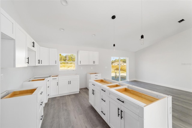 kitchen featuring a kitchen island, decorative light fixtures, light wood-type flooring, and white cabinets