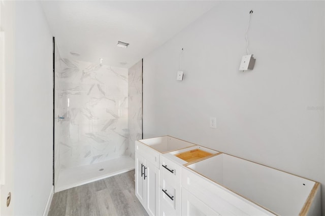 bathroom featuring a tile shower, wood-type flooring, and vanity