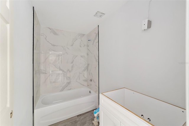 bathroom with hardwood / wood-style flooring and tiled shower / bath