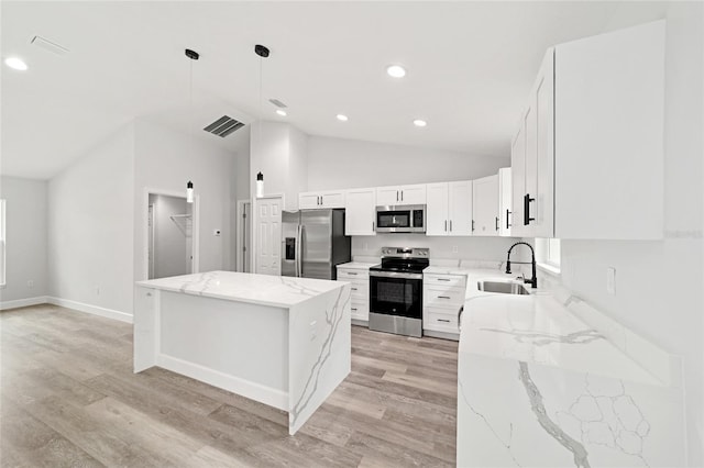 55 Locust Loop Cir, Ocala, FL 34472 - kitchen featuring appliances with stainless steel finishes, vaulted ceiling, a center island, light wood-type flooring, and light stone counters
