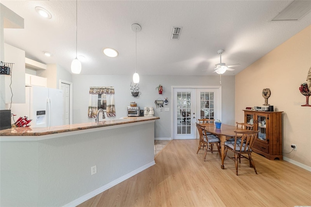 kitchen with french doors, hanging light fixtures, light hardwood / wood-style flooring, kitchen peninsula, and white refrigerator with ice dispenser