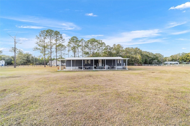 view of front of house featuring a front lawn, a sunroom, and a rural view