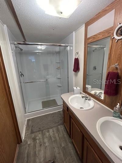 bathroom with an enclosed shower, vanity, hardwood / wood-style flooring, and a textured ceiling