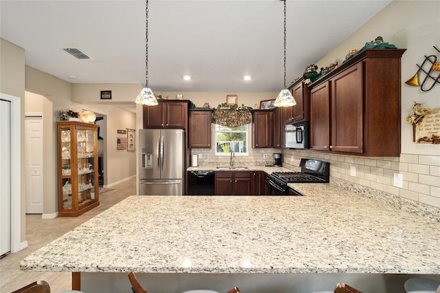 kitchen with black appliances, sink, a kitchen bar, and hanging light fixtures