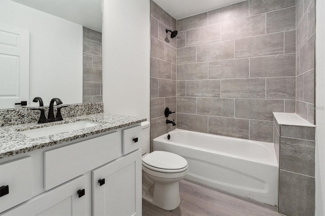 full bathroom with hardwood / wood-style flooring, vanity, toilet, and tiled shower / bath