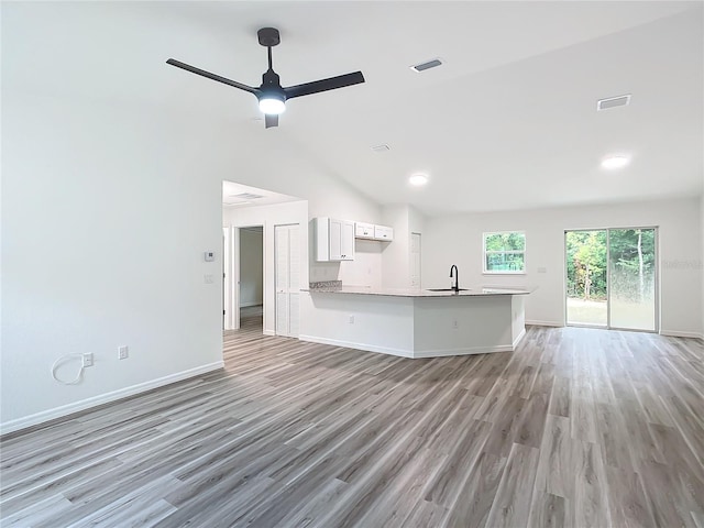 interior space featuring kitchen peninsula, ceiling fan, sink, light hardwood / wood-style floors, and white cabinetry