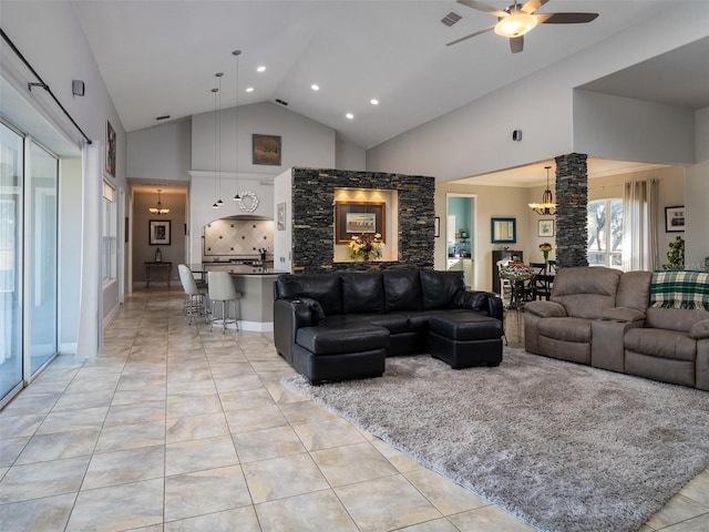 tiled living room featuring ceiling fan with notable chandelier and high vaulted ceiling