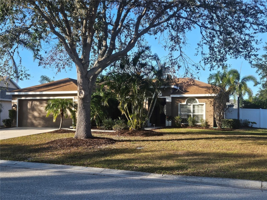 ranch-style home with a garage and a front lawn