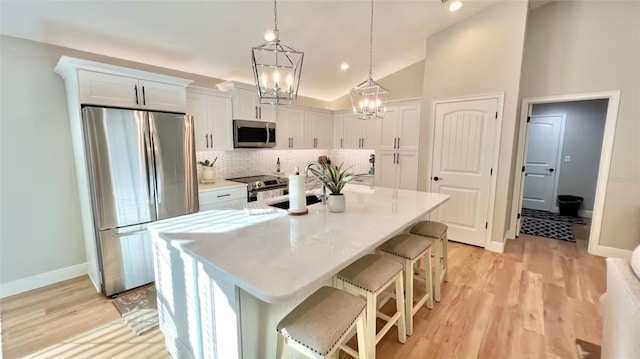 kitchen with a breakfast bar area, stainless steel appliances, backsplash, and white cabinets