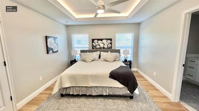 bedroom featuring ceiling fan, hardwood / wood-style flooring, multiple windows, and a tray ceiling