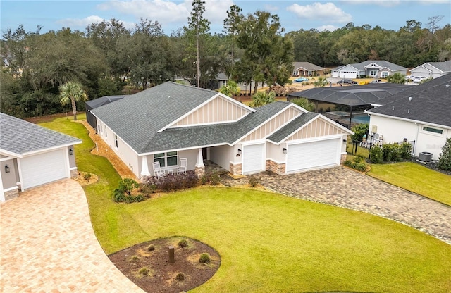 view of front of property with central AC unit, a front lawn, glass enclosure, and a garage