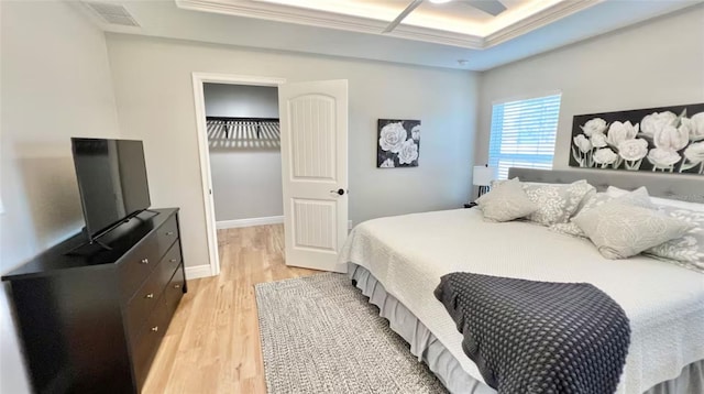 bedroom featuring ornamental molding, light hardwood / wood-style floors, and a raised ceiling