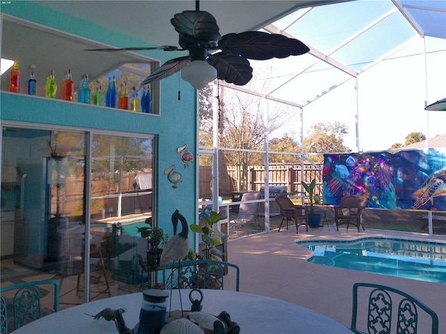 view of swimming pool with ceiling fan, a lanai, and a patio