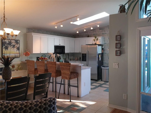 kitchen with stainless steel refrigerator with ice dispenser, light tile patterned floors, pendant lighting, a notable chandelier, and white cabinetry