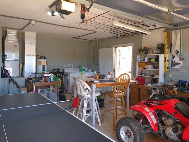 garage featuring a workshop area, electric water heater, a garage door opener, electric panel, and washing machine and dryer