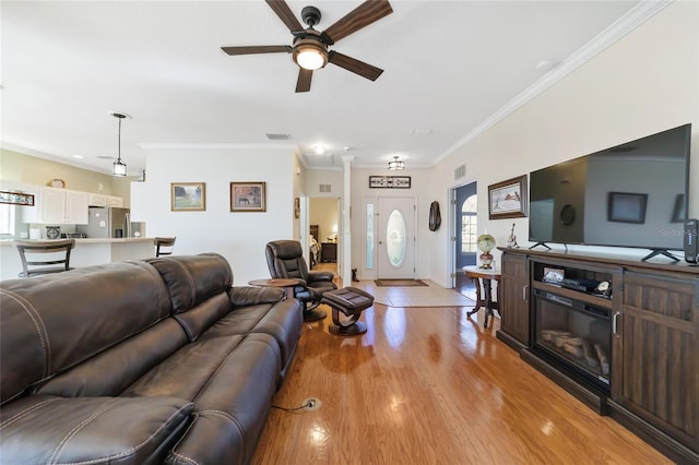 living room featuring light hardwood / wood-style floors, ceiling fan, and ornamental molding