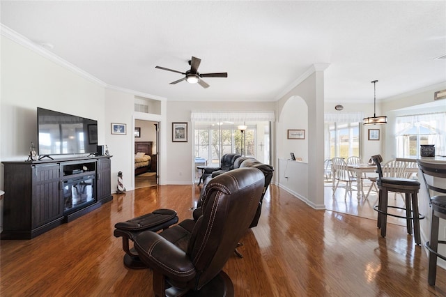 living room with ceiling fan with notable chandelier, hardwood / wood-style flooring, and ornamental molding