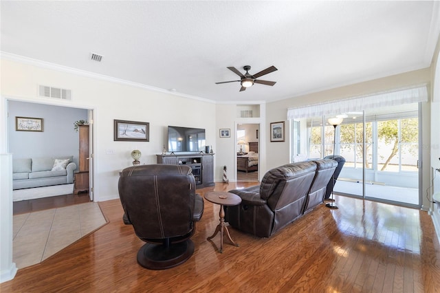 living room featuring ceiling fan, wood-type flooring, and crown molding