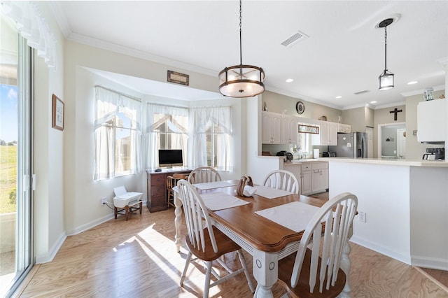 dining area featuring light wood-type flooring, ornamental molding, and a wealth of natural light