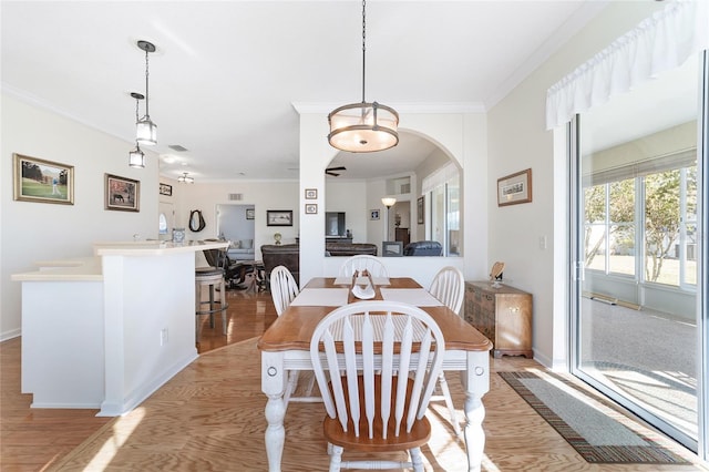 dining room with light wood-type flooring and crown molding