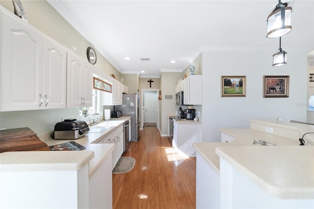 kitchen with kitchen peninsula, appliances with stainless steel finishes, sink, decorative light fixtures, and white cabinets