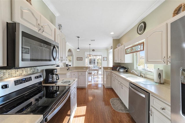 kitchen with white cabinets, sink, dark hardwood / wood-style floors, appliances with stainless steel finishes, and decorative light fixtures