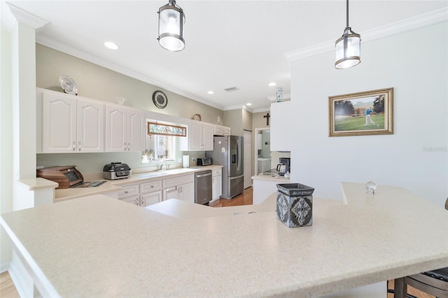 kitchen featuring hanging light fixtures, kitchen peninsula, crown molding, white cabinets, and appliances with stainless steel finishes