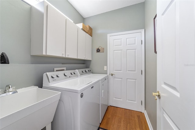 laundry room featuring washer and dryer, cabinets, light wood-type flooring, and sink