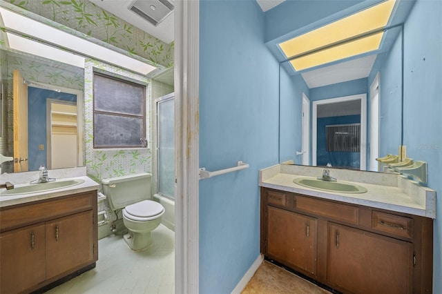 full bathroom featuring vanity, toilet, a skylight, and combined bath / shower with glass door