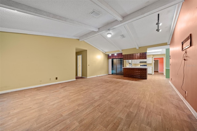 unfurnished living room with lofted ceiling with beams, light wood-type flooring, and a textured ceiling