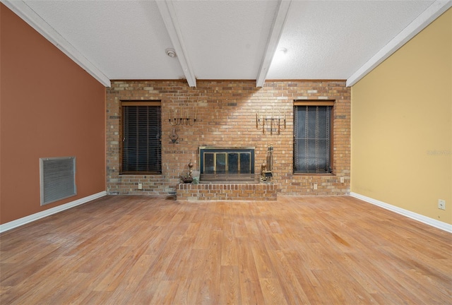 unfurnished living room featuring beam ceiling, a brick fireplace, crown molding, hardwood / wood-style floors, and a textured ceiling