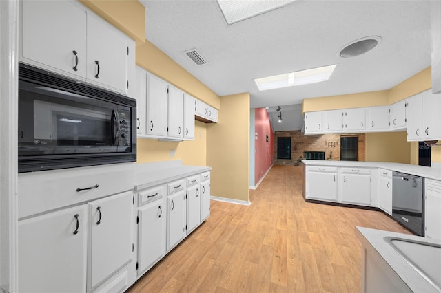 kitchen with white cabinets, a textured ceiling, light hardwood / wood-style floors, and black appliances