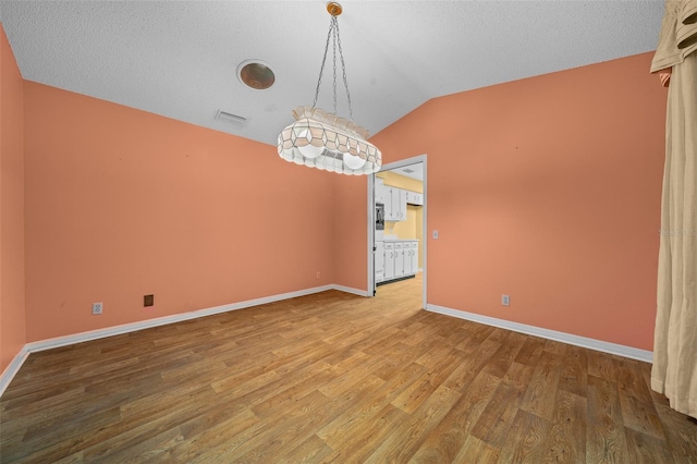 unfurnished dining area featuring wood-type flooring, a textured ceiling, and lofted ceiling