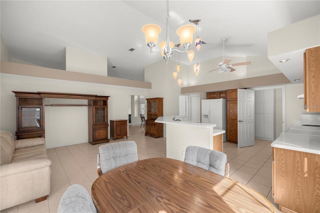 tiled dining area featuring ceiling fan with notable chandelier and high vaulted ceiling