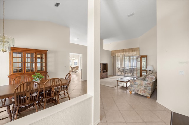 dining room with a chandelier, light tile patterned floors, and high vaulted ceiling