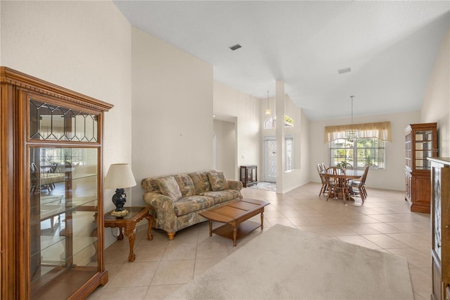 tiled living room with high vaulted ceiling and a notable chandelier