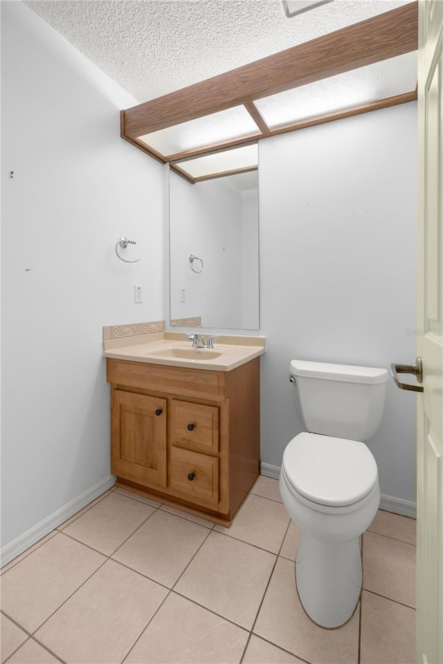 bathroom featuring tile patterned flooring, a textured ceiling, vanity, and toilet