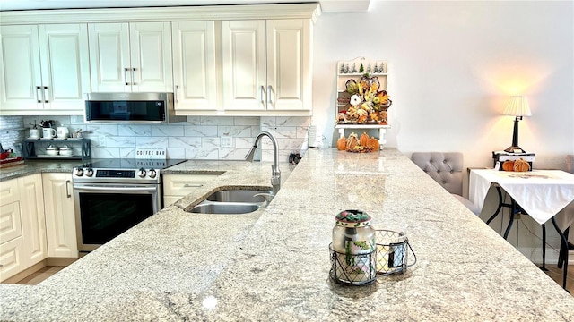 kitchen with sink, stainless steel appliances, decorative backsplash, and light stone countertops