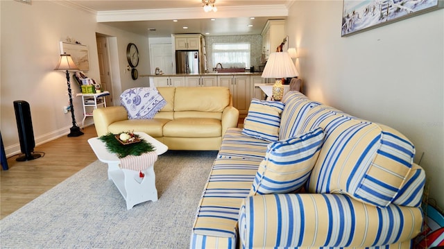 living room with ornamental molding, light hardwood / wood-style flooring, and sink