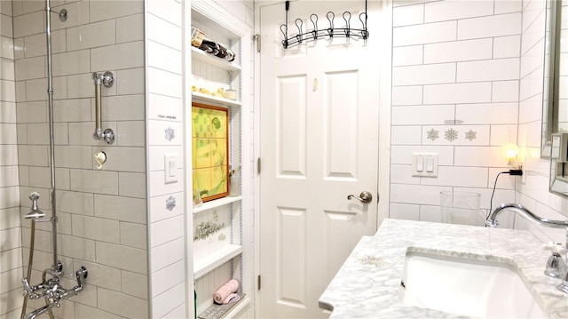 bathroom with built in shelves, a tile shower, and vanity