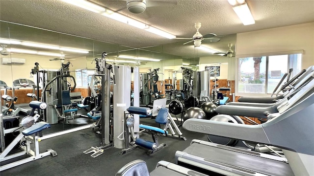 gym featuring a textured ceiling, a wall unit AC, and a healthy amount of sunlight