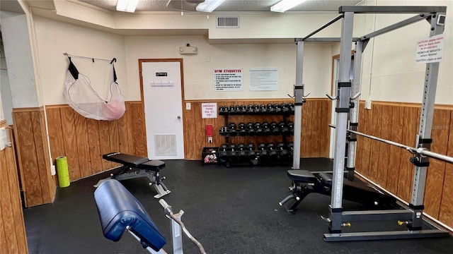 workout area featuring wood walls and a textured ceiling