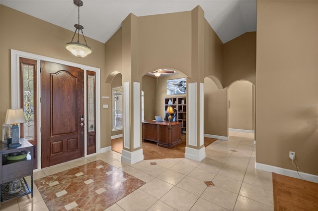 tiled foyer with decorative columns and a towering ceiling