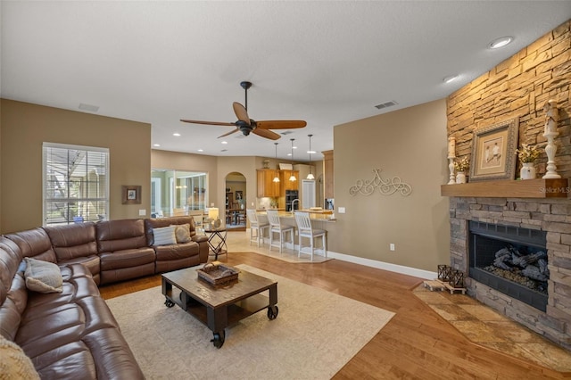 living room with ceiling fan, a fireplace, and light hardwood / wood-style floors