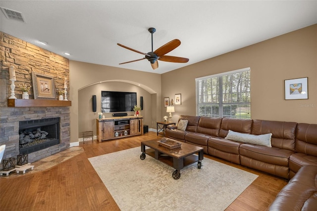 living room featuring ceiling fan, a fireplace, and light hardwood / wood-style flooring